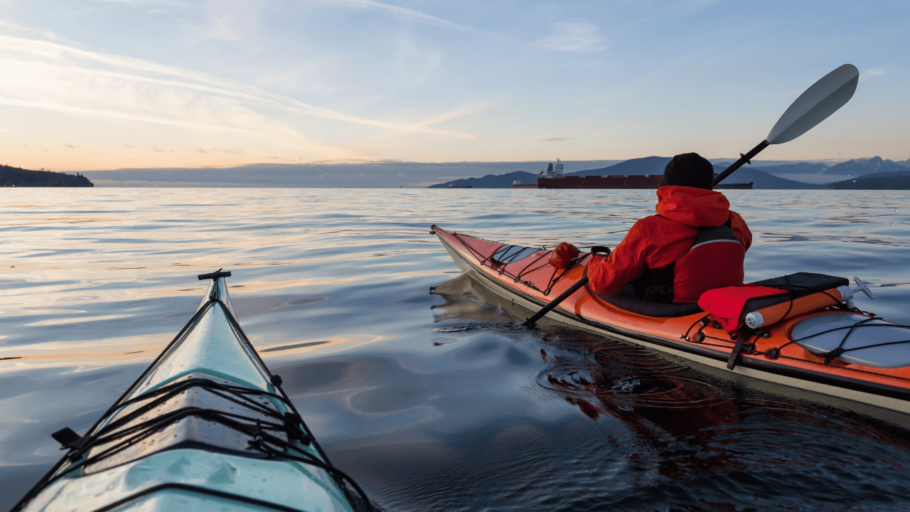two people paddling vibrant sea kayaks during sunset