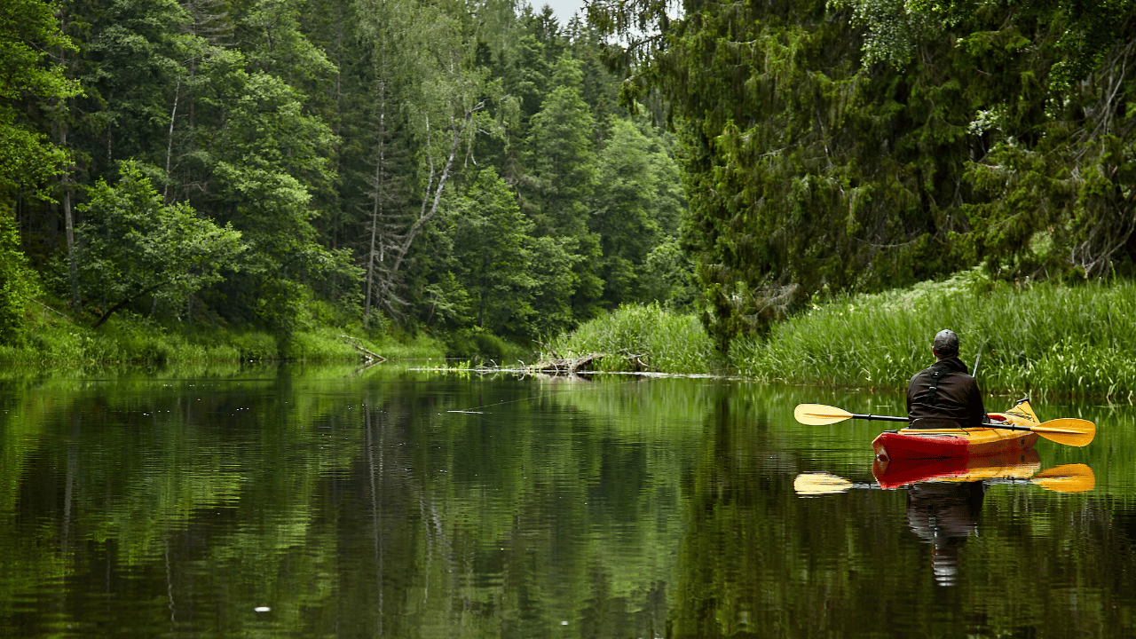 man kayak fishing on a river