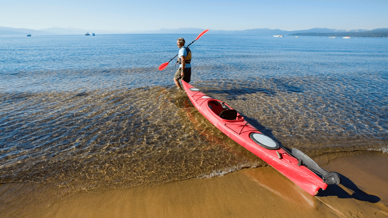 kayaker on shore dragging his kayak into the sea